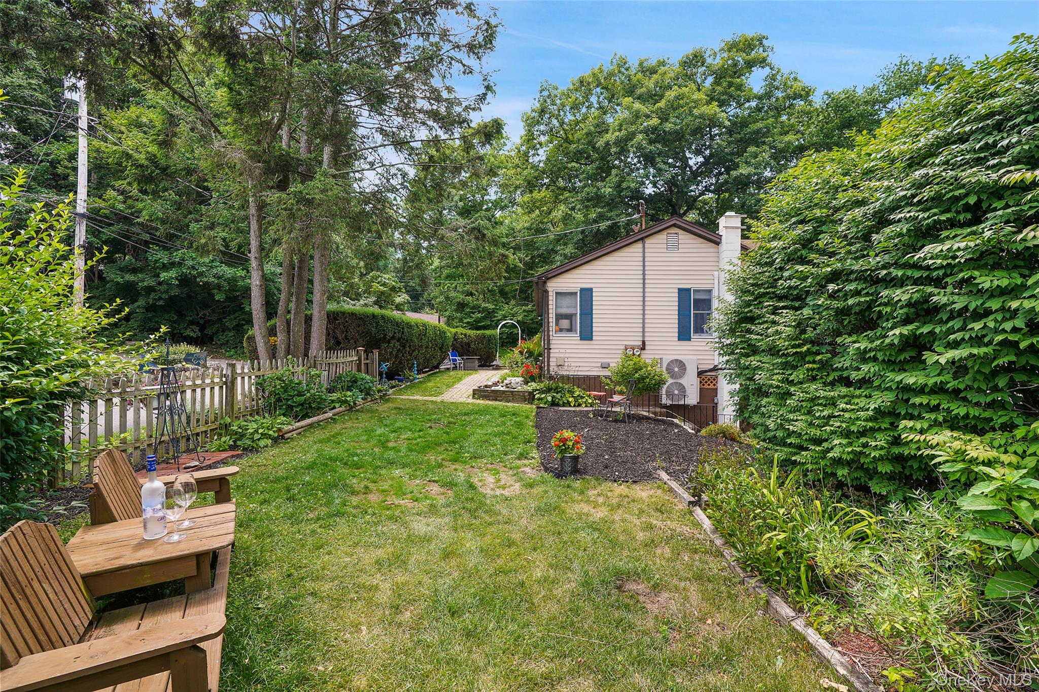 18 Sylvan Road Lake Peekskill, NY 10537 - Photo 43 of 50 Expansive backyard with a manicured lawn, established garden beds, and mature perimeter trees