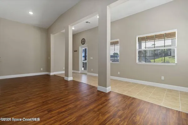 an empty room with wooden floor and windows