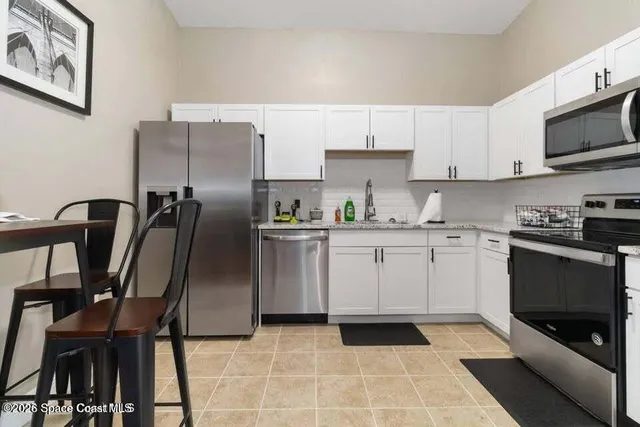 a kitchen with stainless steel appliances a refrigerator sink and white cabinets