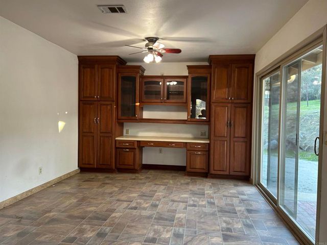 a room with chandelier fan and kitchen view