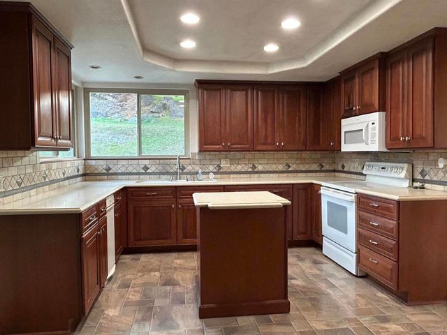 a kitchen with stainless steel appliances granite countertop wooden cabinets a stove top oven a sink and dishwasher