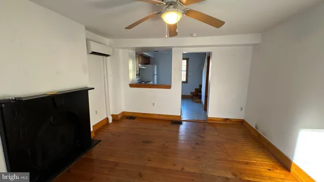 an empty room with wooden floor and ceiling fan