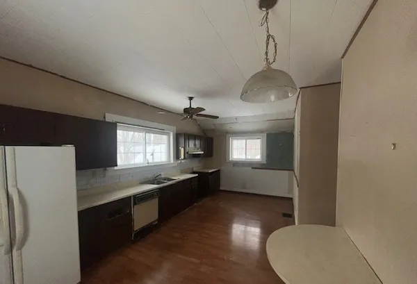 a kitchen with stainless steel appliances granite countertop a refrigerator a sink dishwasher a stove and white countertops with wooden floor