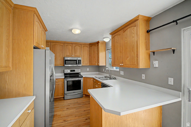 2058 California Avenue, Unit 2 Provo, UT 84606 - Photo 21 of 32 Kitchen featuring light wood cabinetry, stainless steel appliances, solid surface countertops, a double basin sink, and wood-finish flooring