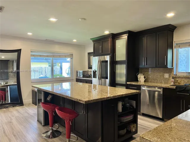 a large kitchen with stainless steel appliances granite countertop a lot of counter space and wooden floor