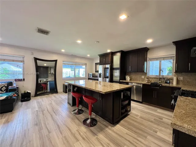 a kitchen with kitchen island a counter top space cabinets and stainless steel appliances