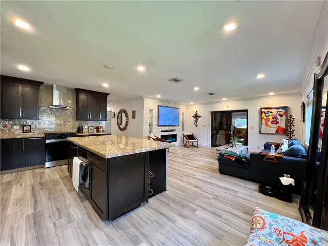 a kitchen with stainless steel appliances kitchen island granite countertop wooden floors and a sink