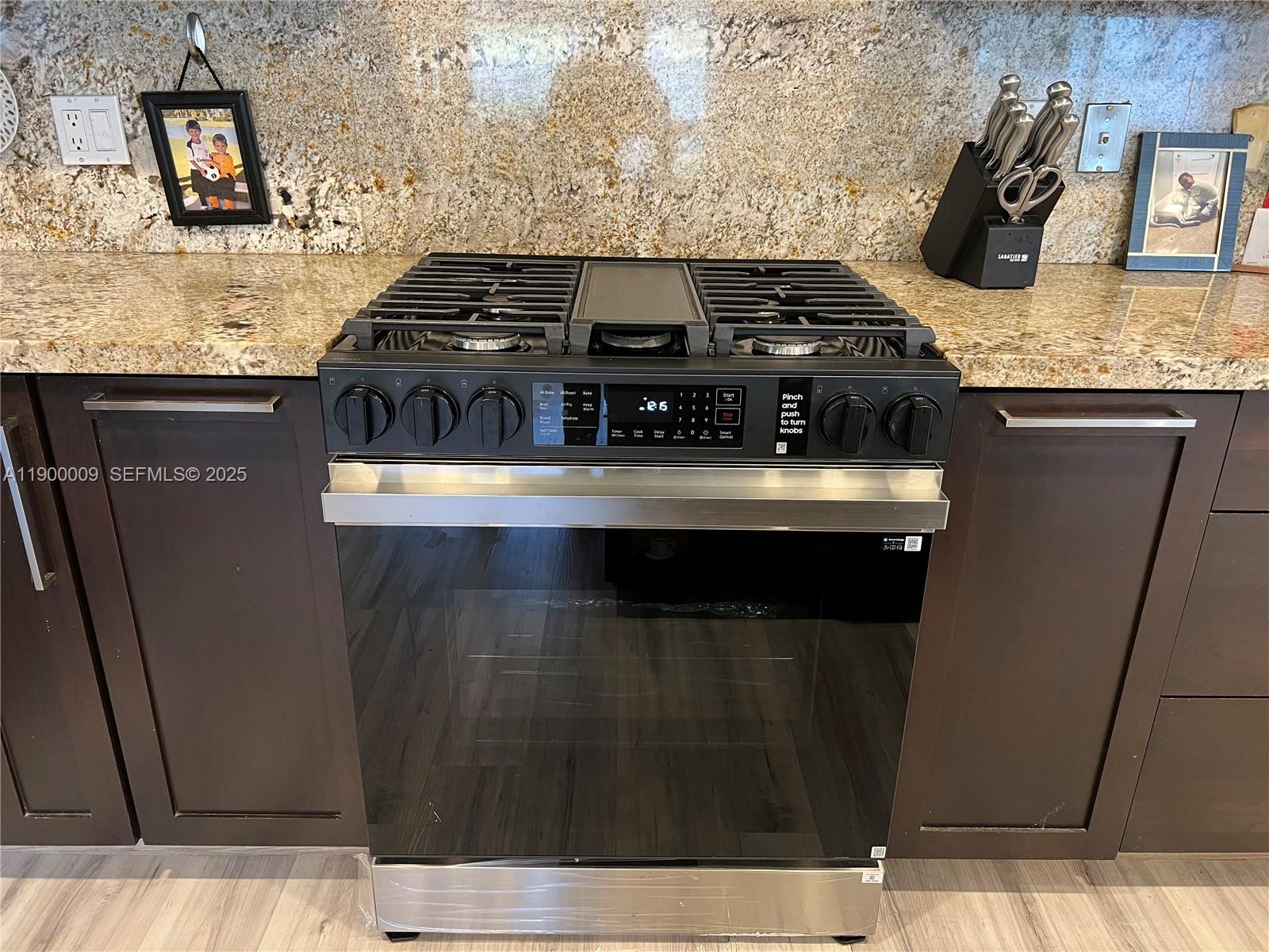 10220 Southwest 160th Street, Unit 10220 Miami, FL 33157 - Photo 20 of 57 a kitchen with granite countertop a stove and cabinets