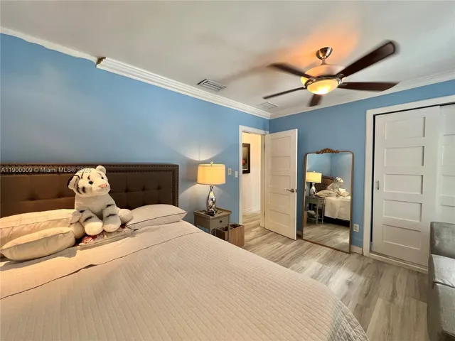 a spacious bedroom with a bed a dresser and a large mirror next to a window