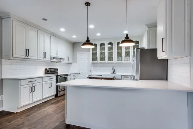 a kitchen with stainless steel appliances granite countertop a refrigerator a sink a stove and white cabinets
