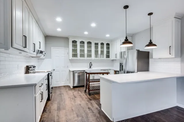 a large kitchen with stainless steel appliances granite countertop a sink a stove and a refrigerator