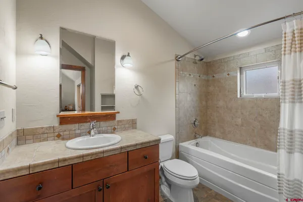 a bathroom with a granite countertop sink toilet mirror and shower