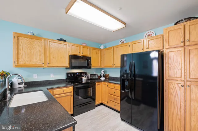a kitchen with granite countertop a refrigerator stove and sink