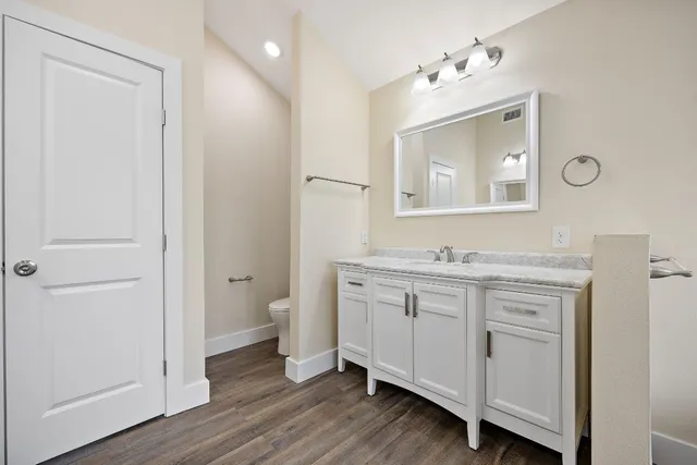 a spacious bathroom with a granite countertop sink toilet and mirror