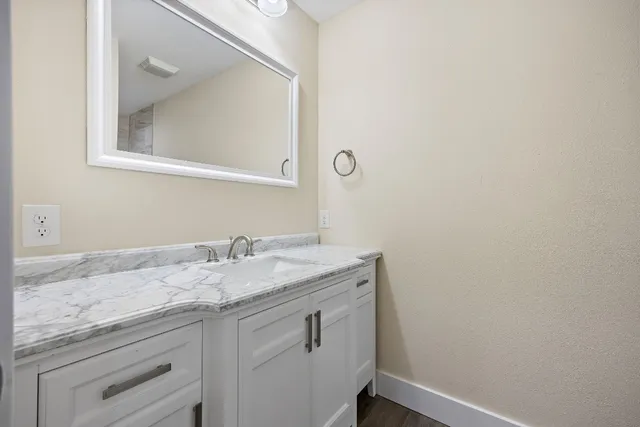 a bathroom with a granite countertop sink and a mirror