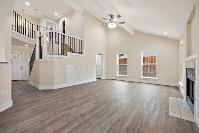 a view of an empty room with wooden floor and a fireplace