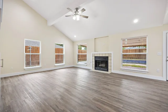 a view of an empty room with wooden floor fireplace and a window