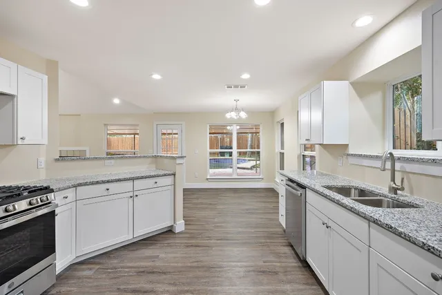 a large kitchen with granite countertop a sink and a stove top oven