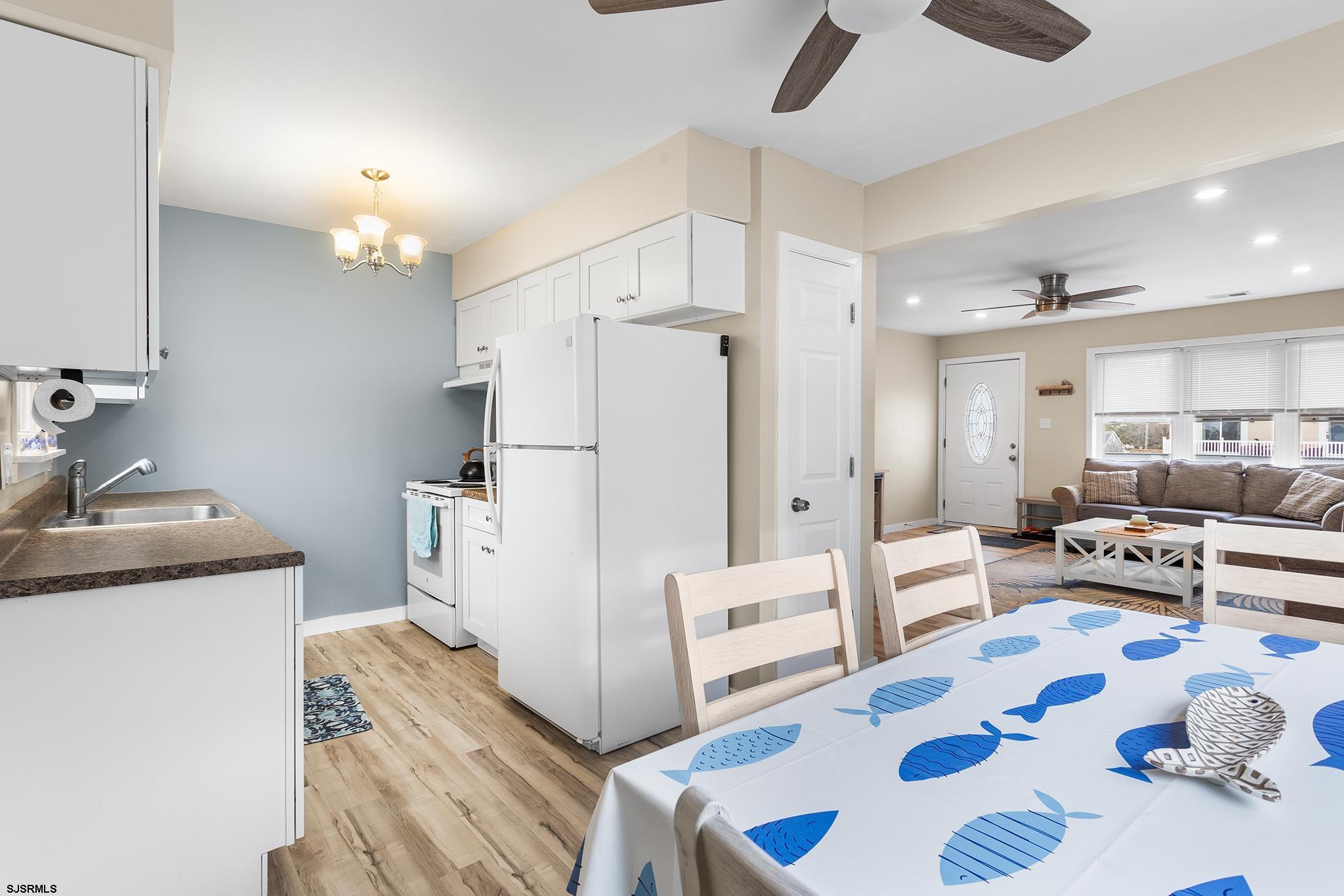 4611 Schooner Road, Unit 2 Brigantine, NJ 08203 - Photo 9 of 25 a kitchen with stainless steel appliances kitchen island granite countertop a refrigerator and a dining table with wooden floor