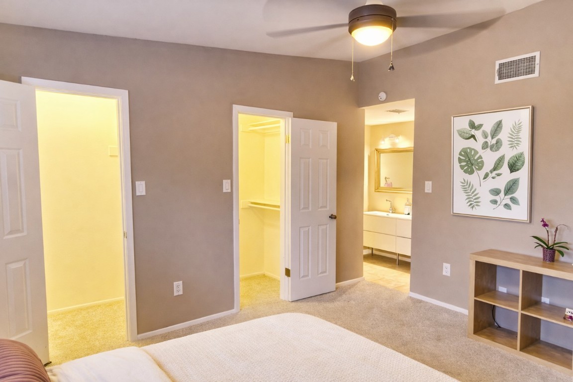 1501 Barton Springs Road, Unit 240 Austin, TX 78704 - Photo 16 of 23 Bedroom with a walk in closet, connected bathroom, light colored carpet, and a ceiling fan