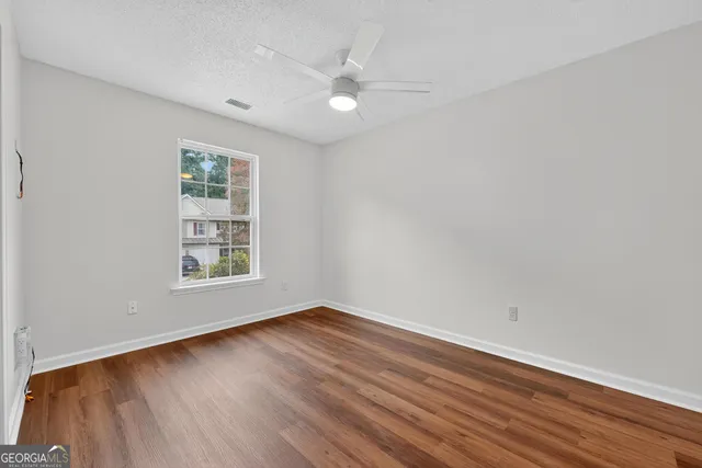an empty room with wooden floor and windows