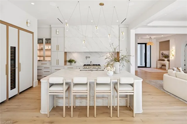 a kitchen with stainless steel appliances kitchen island granite countertop a dining table chairs and a refrigerator