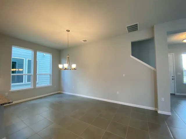 an empty room with chandelier fan and windows