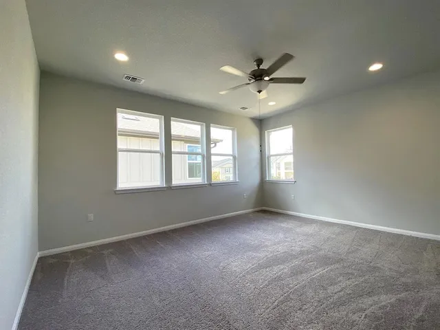 an empty room with chandelier fan and windows