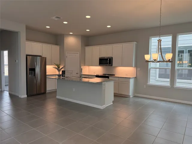 a large kitchen with stainless steel appliances a refrigerator and a stove top oven