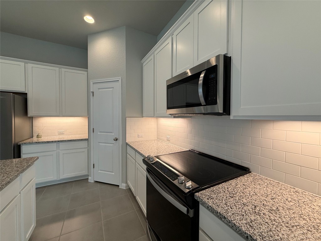 320 Creek Road, Unit 303 Dripping Springs, TX 78620 - Photo 6 of 28 a kitchen with granite countertop a sink and steel appliances