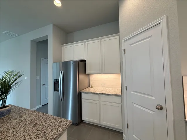 a kitchen with white cabinets and refrigerator
