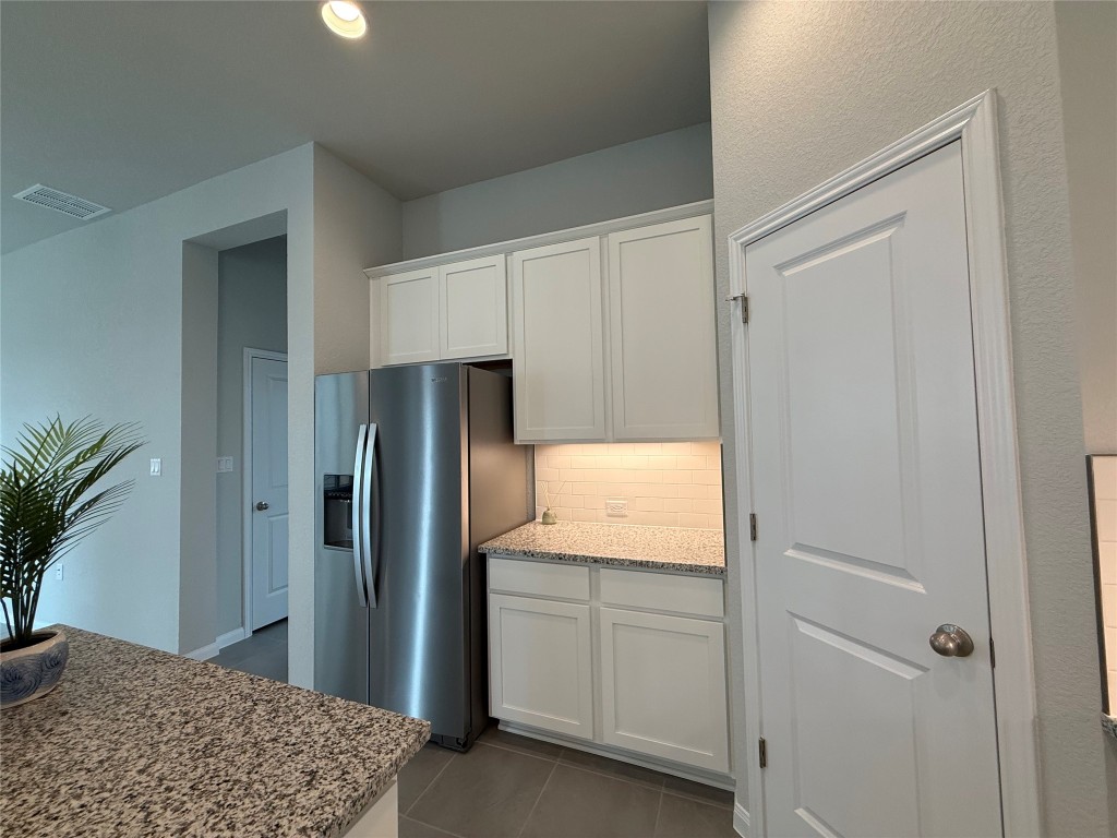 320 Creek Road, Unit 303 Dripping Springs, TX 78620 - Photo 7 of 28 a kitchen with white cabinets and refrigerator