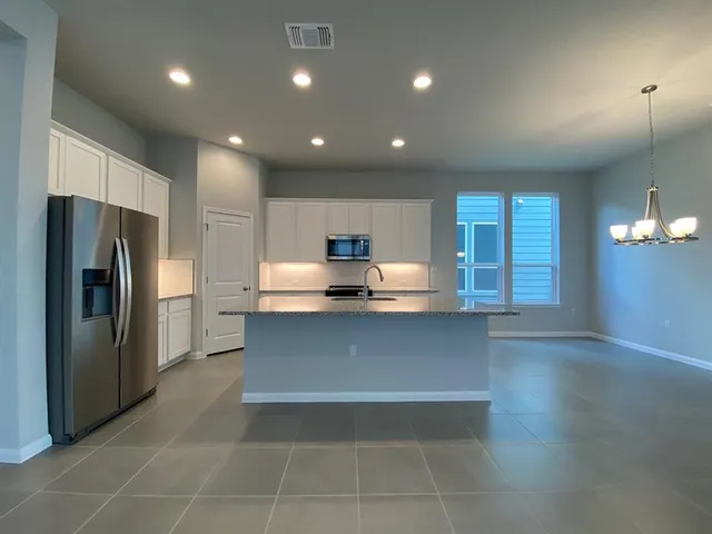 a kitchen with stainless steel appliances a refrigerator and a wooden floor