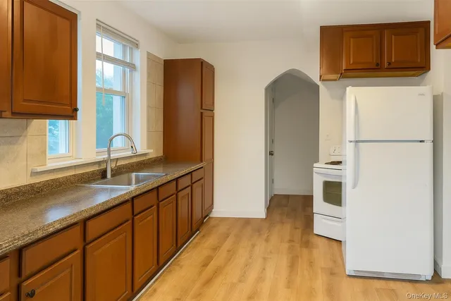 a kitchen with stainless steel appliances granite countertop a refrigerator a stove and a sink with large window