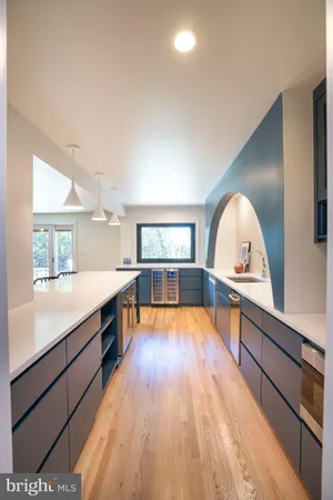 a view of a living room kitchen with a large window and wooden floor