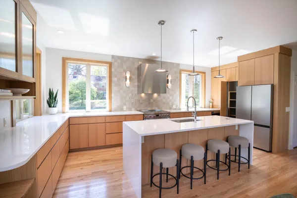a kitchen with stainless steel appliances granite countertop a table chairs sink refrigerator and wooden floor