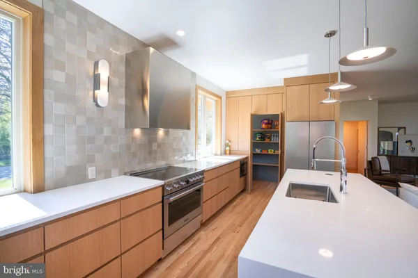 a large kitchen with stainless steel appliances a large counter top a stove and a refrigerator
