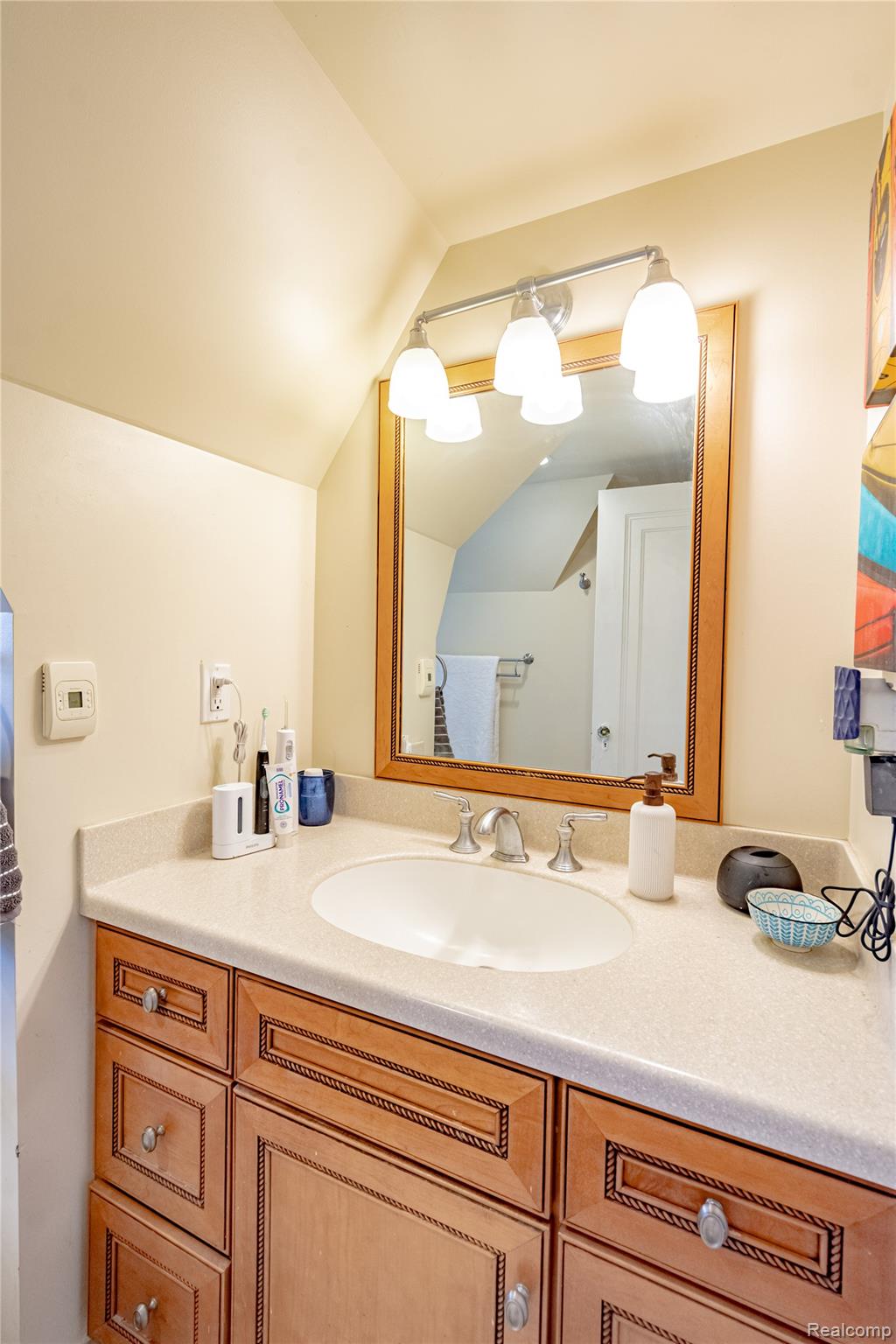 5630 Lakeshore Road Fort Gratiot, MI 48059 - Photo 31 of 49 Bathroom vanity featuring a light-colored countertop, an undermount sink with a chrome faucet, and a wood-framed mirror