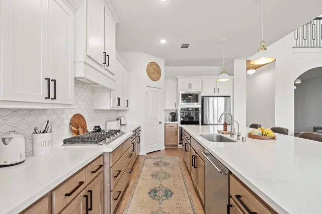 a kitchen with a dining table chairs cabinets and stainless steel appliances
