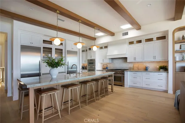 a kitchen with stainless steel appliances kitchen island granite countertop a table chairs stove and cabinets