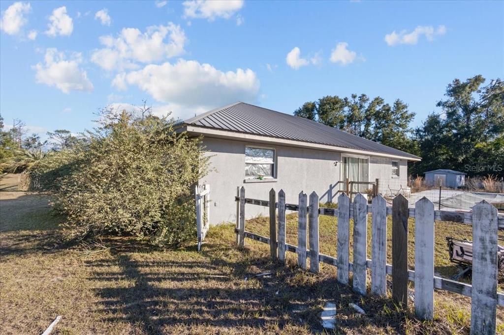 13691 201st Road Live Oak, FL 32060 - Photo 24 of 36 a view of a blue house with a yard and lawn chairs under an umbrella