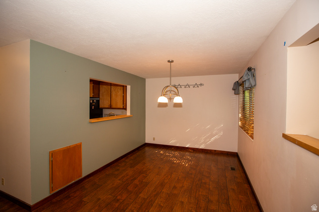 1500 Sumac Drive Logan, UT 84321 - Photo 14 of 42 Dining room featuring wood-finish flooring, a pass-through window with wood trim, and a contemporary chandelier