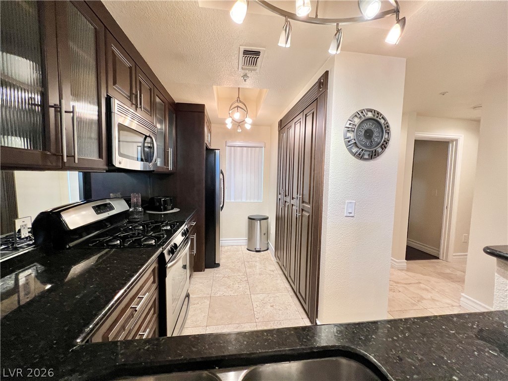 270 East Flamingo Road, Unit 313 Las Vegas, NV 89169 - Photo 7 of 27 Culinary delights await in this sleek kitchen, featuring dark wood cabinetry and black granite surfaces.