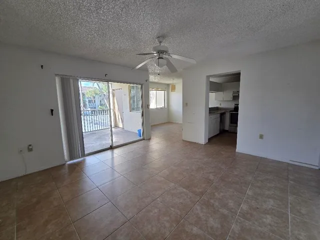 an empty room with chandelier fan and windows