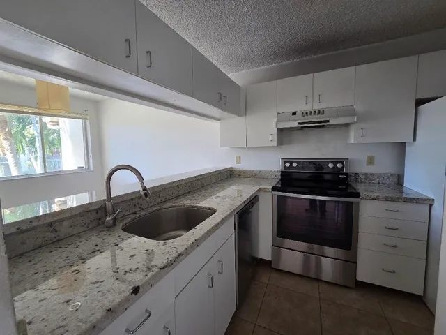 a kitchen with granite countertop a sink and cabinets