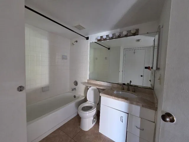 a bathroom with a granite countertop sink a toilet and shower