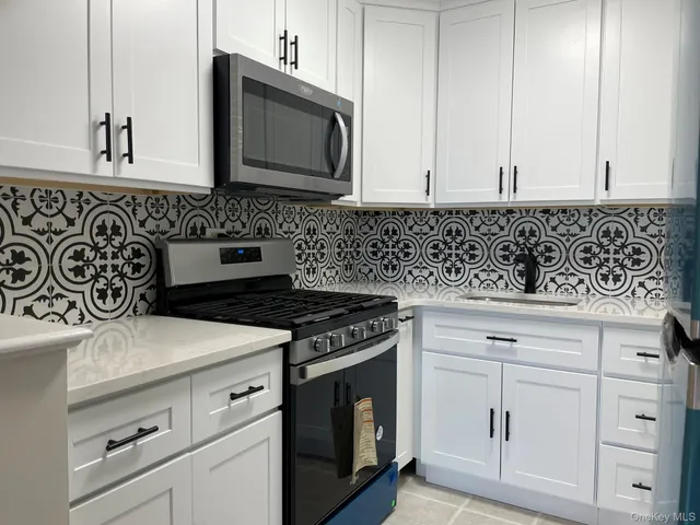 a kitchen with granite countertop white cabinets and stainless steel appliances