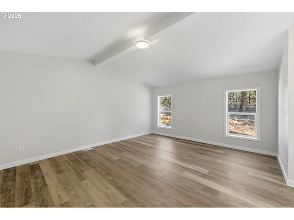 a view of an empty room with a window and wooden floor
