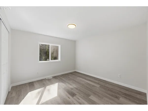 an empty room with wooden floor and windows