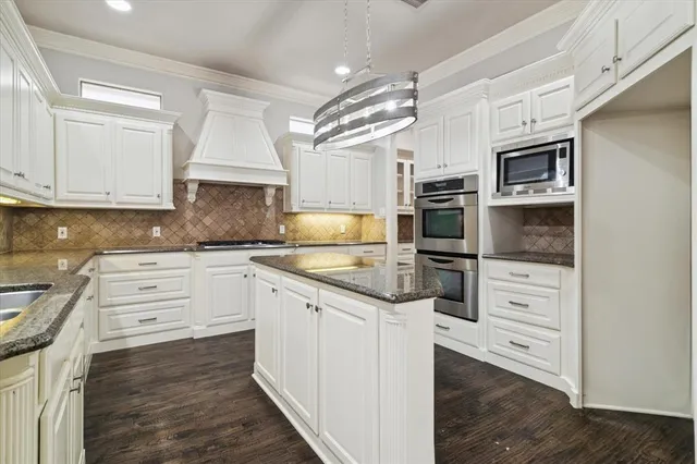 a kitchen with granite countertop white cabinets and stainless steel appliances